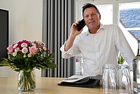 Herr Hilker mit einem Telefon in der Hand an seinem Schreibtisch im Rathaus