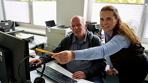 Julia Tewes zeigt Michael Hilgenböker etwas auf ihrem Bildschirm an ihrem Arbeitsplatz in der Ausländerbehörde der Stadt Detmold