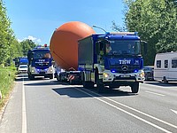 Blaue THW-Fahrzeuge bergen die "rote Kugel" (Kunstwerk im öffentlichen Raum) in Detmold auf einem Anhänger 