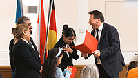 Das Foto zeigt Bürgermeister Frank Hilker bei der Überreichung von Einbürgerungsurkunden an neue Detmolderinnen und Detmolder