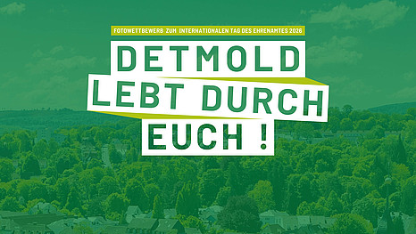 Luftaufnahme über Detmold mit einem dunkelgrünen Overlay und den Worten "Detmold lebt durch euch!" und "Fotowettbewerb zum internationalen Tag des Ehrenamtes 2026" darauf 