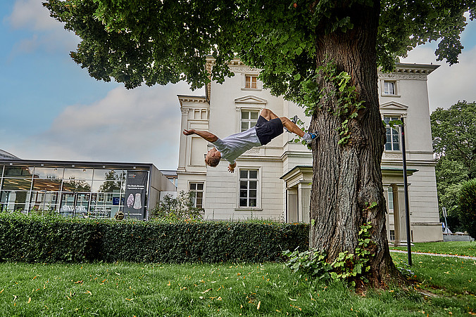 Ein junger Mann macht einen Flic Flac vor dem Landesmuseum Detmold
