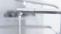 Ein silberner Wasserhahn aus welchem Wasser läuft