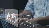 Hände tippen auf einem Laptop und davor sind E-Mail-Icons zu sehen