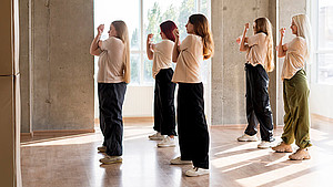 Sechs junge Mädchen dehnen ihre Arme in einer Tanzhalle