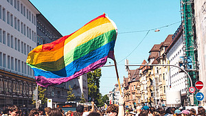 Die Regenbogenflagge wird von einer Menschenmenge in die Luft gehalten