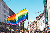 Die Regenbogenflagge wird von einer Menschenmenge in die Luft gehalten