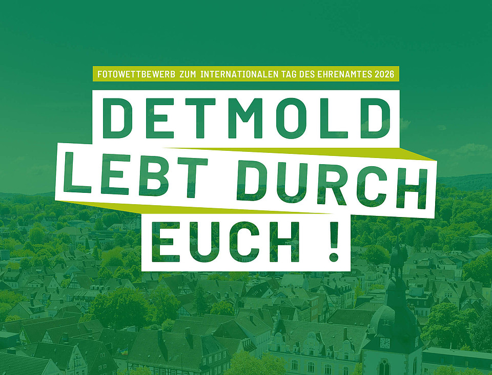 Luftaufnahme über Detmold mit einem dunkelgrünen Overlay und den Worten "Detmold lebt durch euch!" und "Fotowettbewerb zum internationalen Tag des Ehrenamtes 2026" darauf