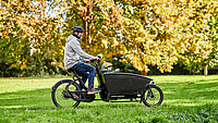 Ein Vater auf einem Lastenfahrrad, in welchem vorne sein Sohn sitzt