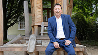 Bürgermeister Frank Hilker sitz auf einem Klettergerüst aus Holz
