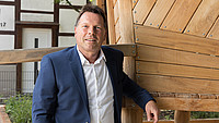 Bürgermeister Frank Hilker lehnt an einem Holzgerüst