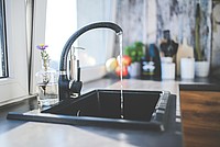 Ein schwarzer Wasserhahn aus dem Wasser herausläuft