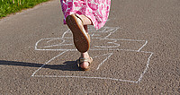 Straßenansicht von Kinderfüßen beim Kästchenhüpfen