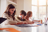 Drei Kinder unterschiedlichen Geschlechts sitzen an einem Tisch und basteln