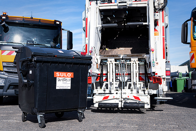 Drei Müllabfuhrfahrzeuge und eine schwarze Containertonne auf dem Bau- und Betriebshof der Stadt Detmold