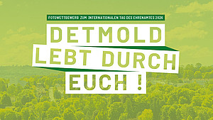 Luftaufnahme über Detmold mit einem hellgrünen Overlay und den Worten "Detmold lebt durch euch!" und "Fotowettbewerb zum internationalen Tag des Ehrenamtes 2026" darauf 
