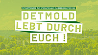 Luftaufnahme über Detmold mit einem hellgrünen Overlay und den Worten "Detmold lebt durch euch!" und "Fotowettbewerb zum internationalen Tag des Ehrenamtes 2026" darauf 