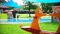 Nahaufnahme einer orangenen Kinderwippe auf einem Freibadgelände in Detmold