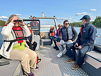Aufnahme von mehreren Personen auf einem Boot bei einer Bootstour in den Nationalpark Linnansaari