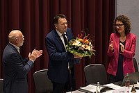Kämmerin und erste Beigeordnete Dr. Miriam Mikus (links) und Alterspräsident Rainer Friedrich (rechts) applaudieren Bürgermeister Frank Hilker (mitte), welcher einen Blumenstrauß in den Händen hält