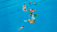 Luftaufnahme von neun Kindern und drei Erwachsenen in einem Schwimmbecken
