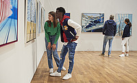 Menschen schauen sich Bilder in einer Galerie an.