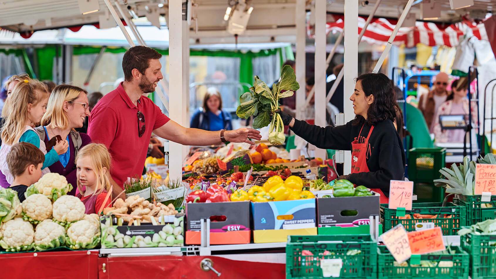 Eine Marktbeschickerin überreicht einem Mann auf dem Wochenmarkt in Detmold Gemüse