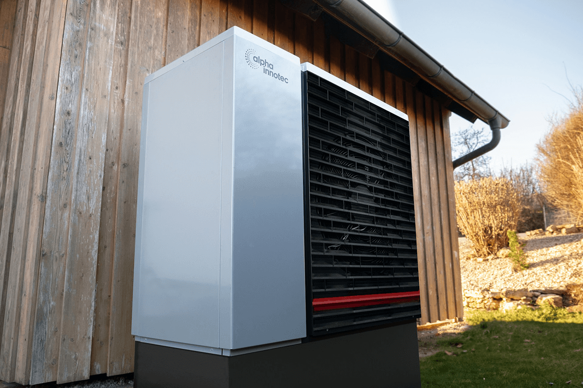 Nahaufnahme einer Wärmepumpe an einem Holzhaus