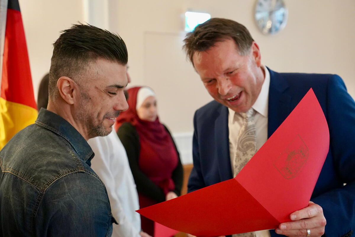 Bürgermeister Frank Hilker überreicht die Einbürgerungsurkunde einem neuen Detmolder