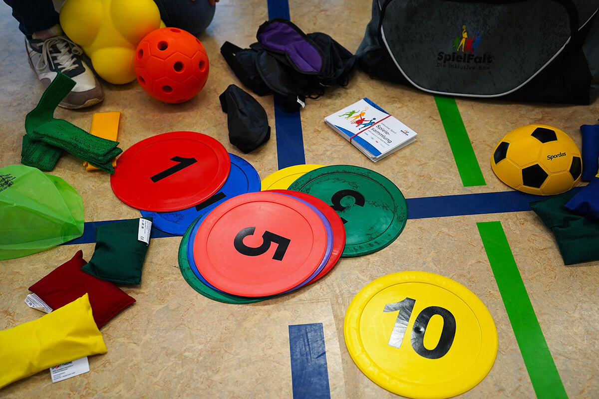 Die Materialien der „SpielFalt“-Sporttasche, von Augenbinden über Glockenball bis Reaktionsball.
