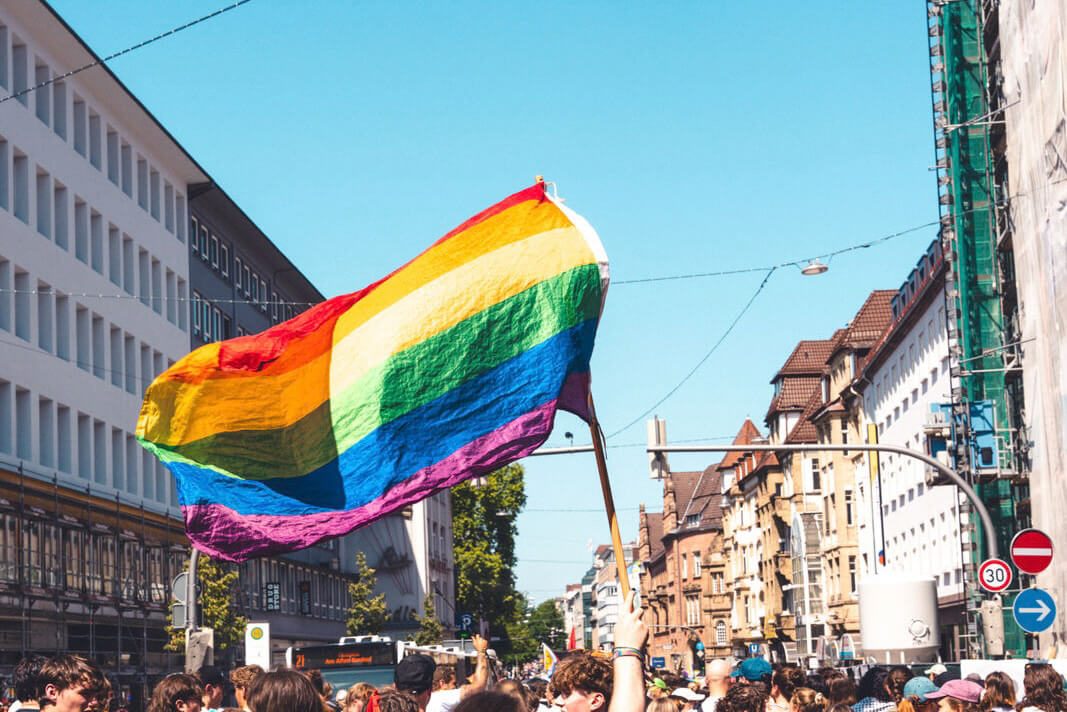 Die Regenbogenflagge wird von einer Menschenmenge in die Luft gehalten